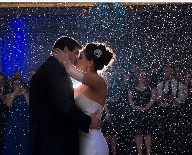 Bride and groom sharing a first dance surrounded by falling snow